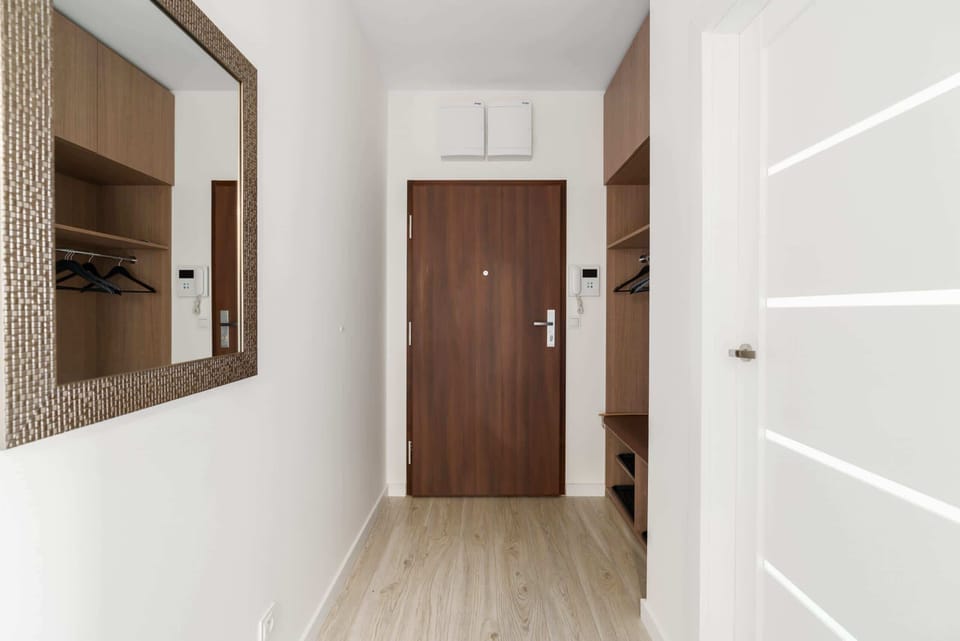 An entryway with a large wall mirror and sleek decor, providing a warm welcome.

