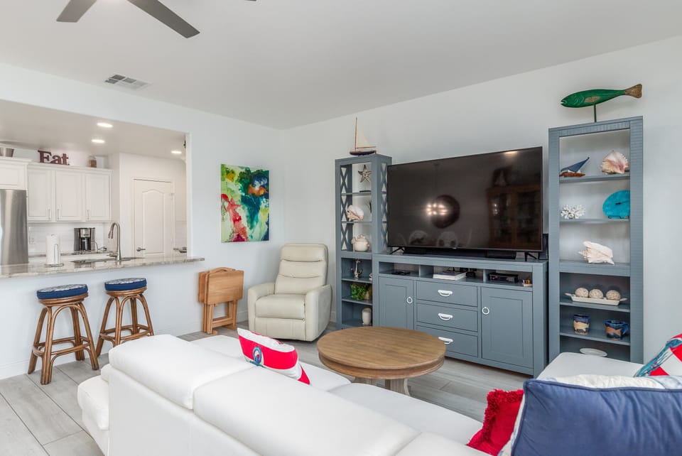 Relax in your bright, coastal-themed living space with modern entertainment center and open kitchen for memorable vacation moments.