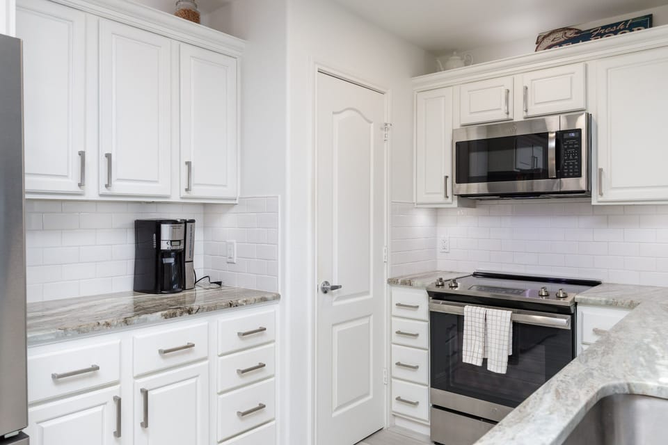 Cook your favorite meals in this bright, fully-equipped kitchen with granite countertops and modern stainless steel appliances.