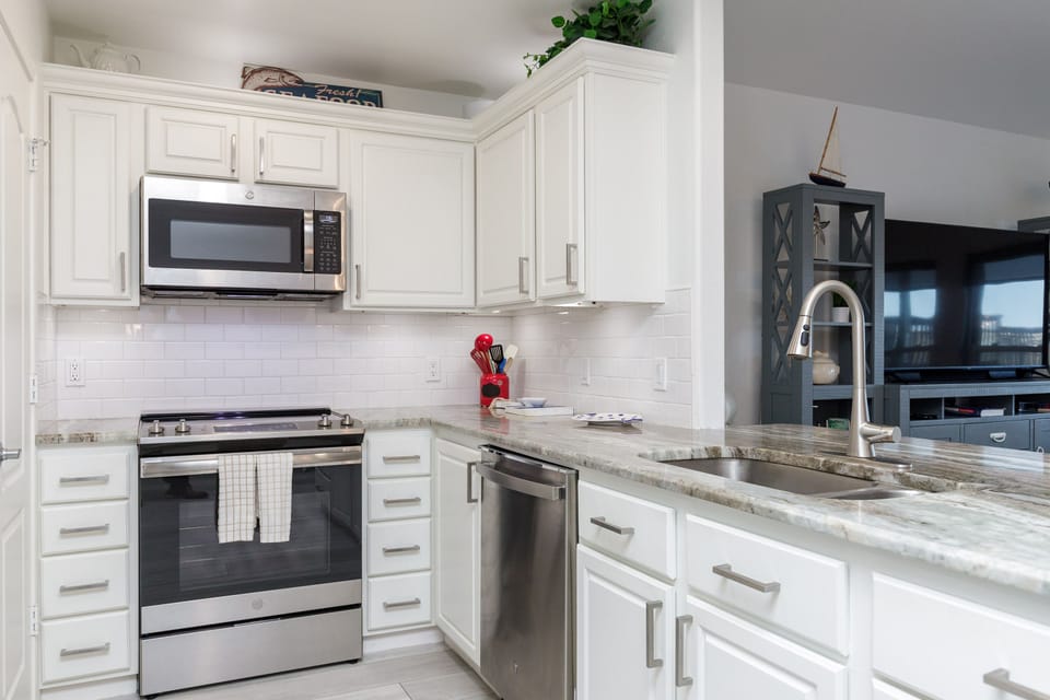 Your fully equipped kitchen with granite countertops, stainless steel appliances, and bright white cabinetry invites culinary adventures during your stay.