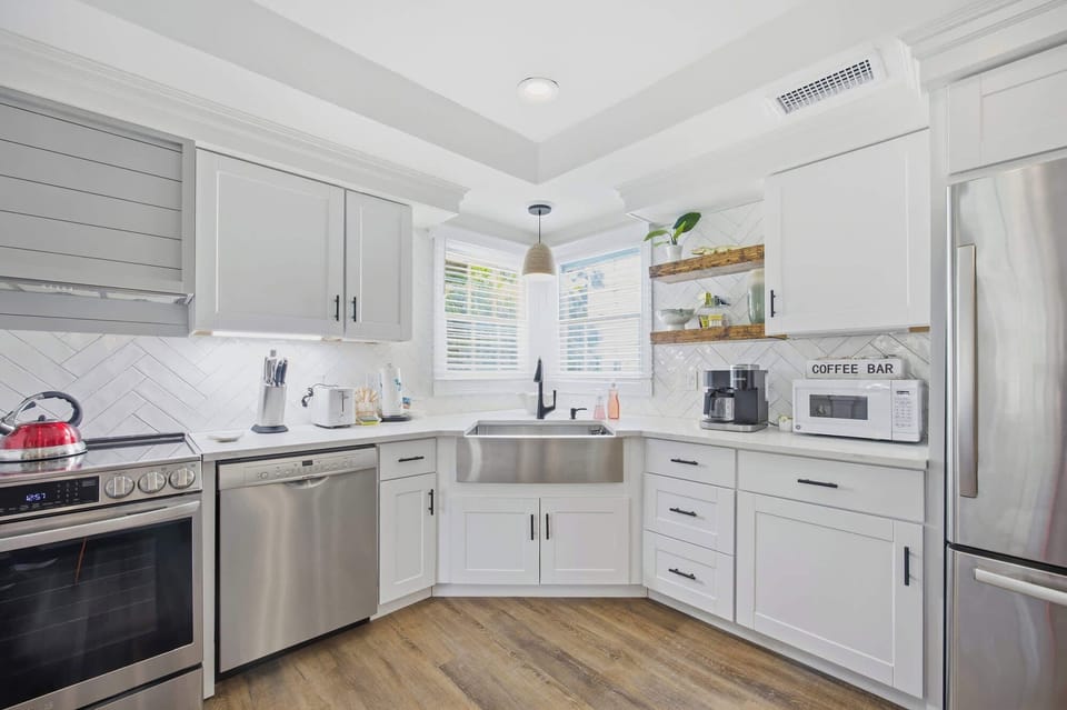 Modern kitchen with stainless steel appliances and a farmhouse sink under bright corner windows