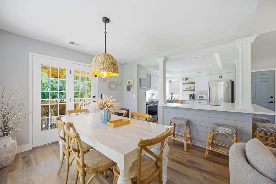 Dining area with natural light and a woven pendant light overlooking the kitchen and outdoor seating.