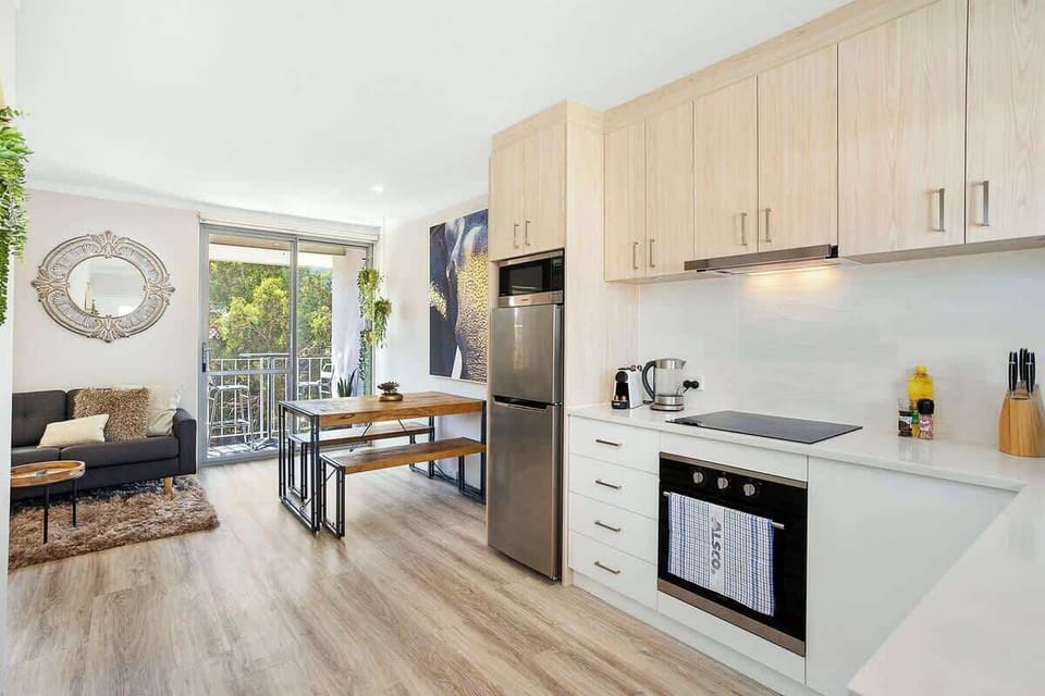 This cozy apartment features a fully equipped kitchen with modern cabinets, a sleek stove and oven, a refrigerator, an espresso machine, electric kettle, salt and knife set, and a dining table. 