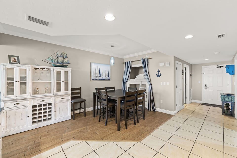 Gather around the dining table for meals and conversation in this bright, nautical-themed space. Coastal touches like the ship model and anchor decor create a relaxing seaside vibe.