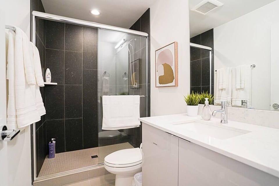 The master suite has an en-suite bathroom, which features a tiled walk-in shower, a large vanity sink, and plenty of counter space