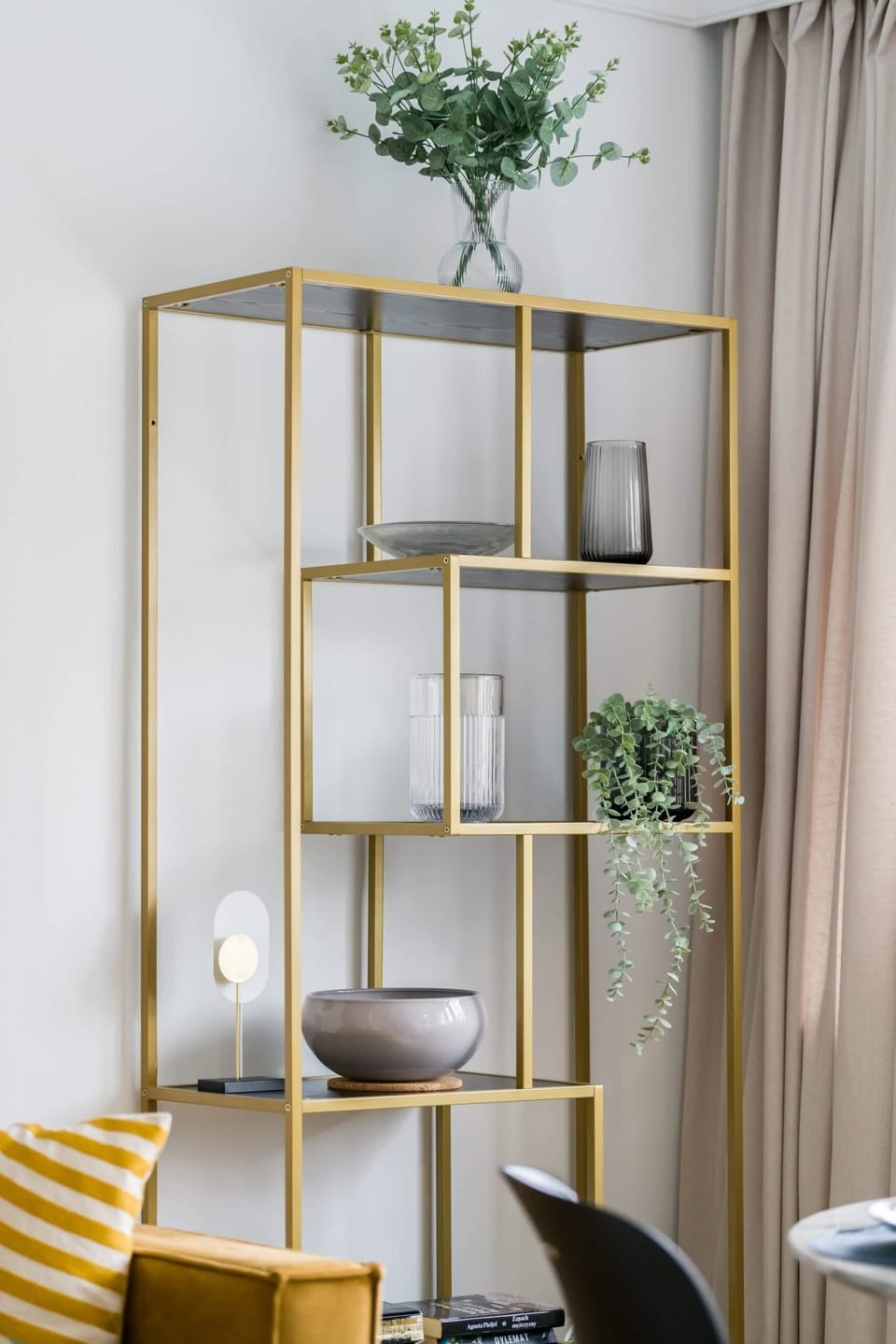 A decorative shelf with golden accents and greenery, bringing a fresh touch to the interior.

