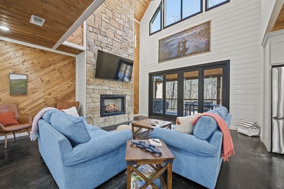 Living Room: Bright, spacious retreat with vaulted ceilings, stone fireplace, and forest views!
