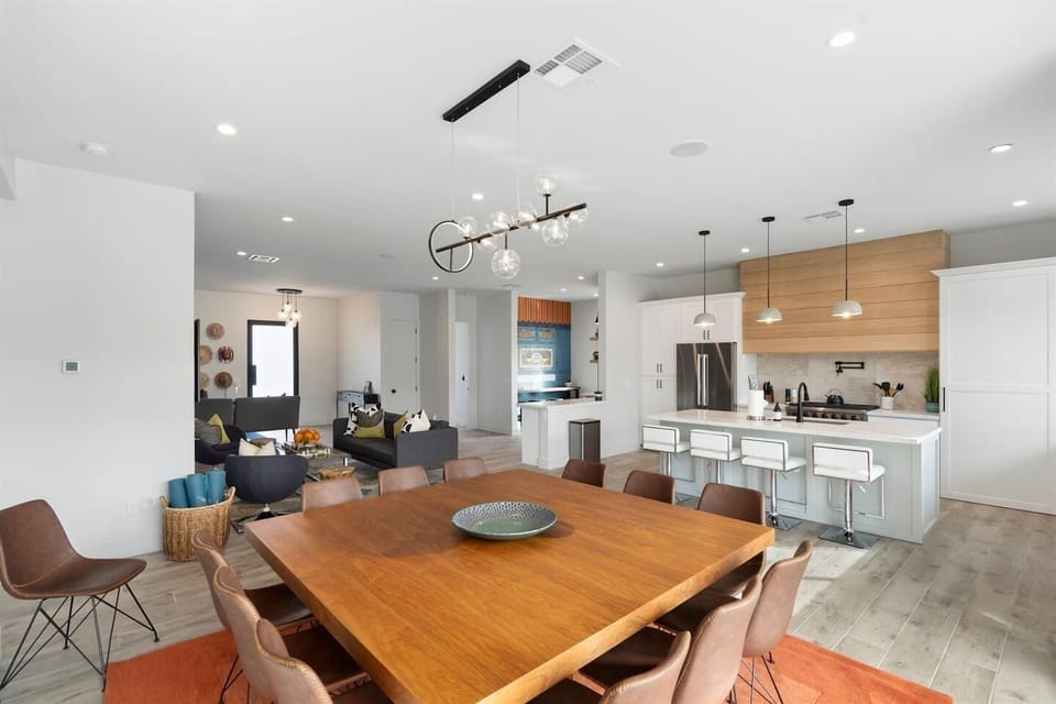 The spacious 12-seater wood-themed dining table invites you to enjoy meals outdoors, with the pool and kitchen just steps away, creating a perfect setting for entertaining.