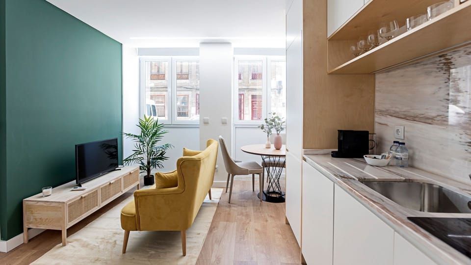 Unwind in the vibrant living area, featuring a comfortable sofa and a dedicated dining space, ideal for relaxing evenings or enjoying a home-cooked meal. Large windows fill the room with natural light, creating a bright and inviting atmosphere for all gue