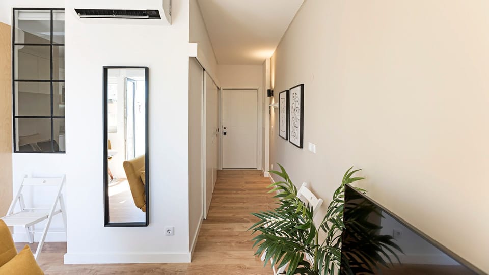 Step into your private sanctuary through a clean, modern hallway, offering ample storage with built-in wardrobes and a full-length mirror to check your look before heading out to explore Porto. #ApartmentEntrance #ModernHallway #StorageSolutions #FullLeng