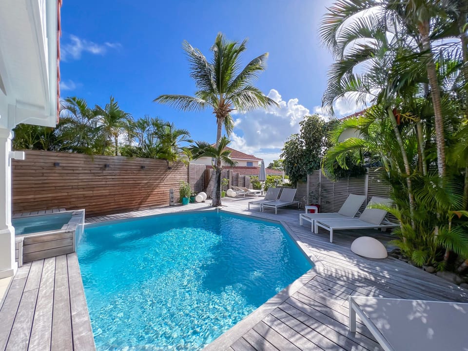 Salt pool and wooden terrace with deckchairs and tropical garden