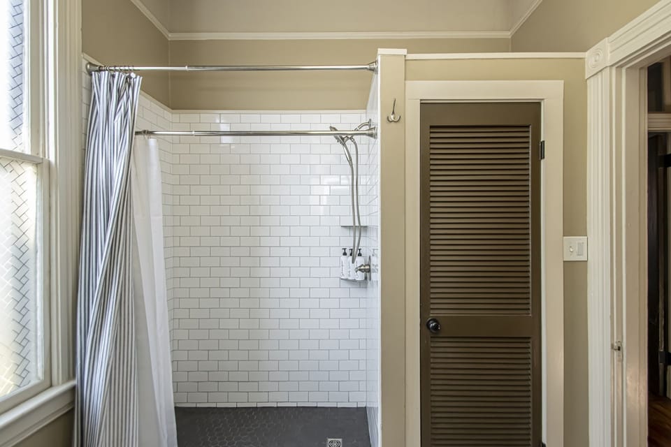 Shower closet stores extra linens, laundry detergent, iron and ironing board.