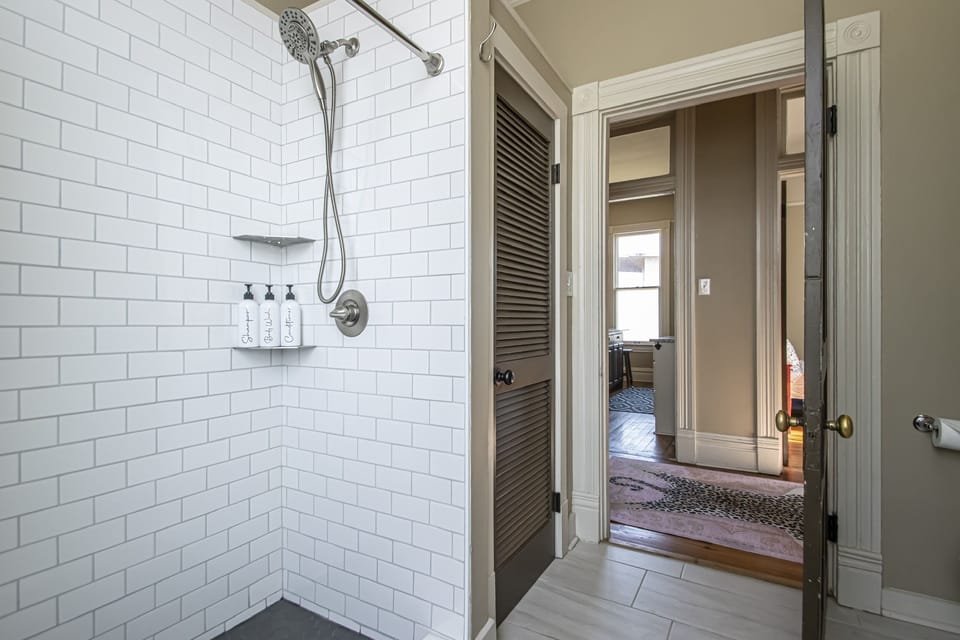 Tiled walk in shower with shampoo, conditioner and body wash.
