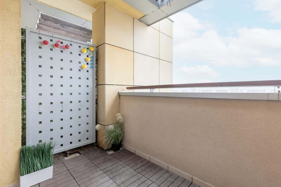 A balcony with a privacy screen, potted plants, and a view of the outdoors.
