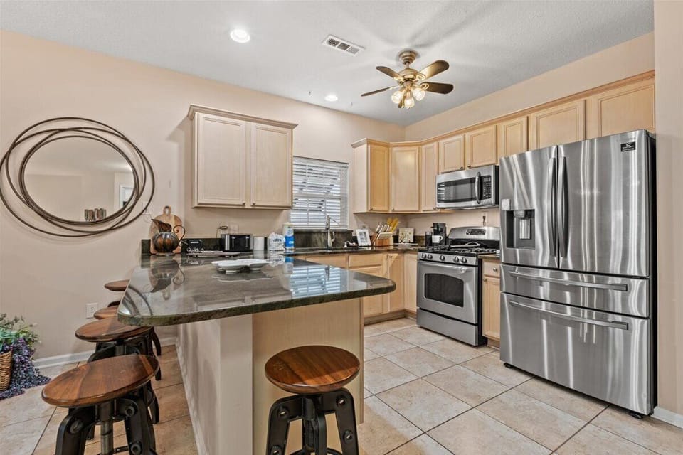 Your fully equipped kitchen features gleaming granite counters, stainless steel appliances, and a breakfast bar perfect for morning coffee.