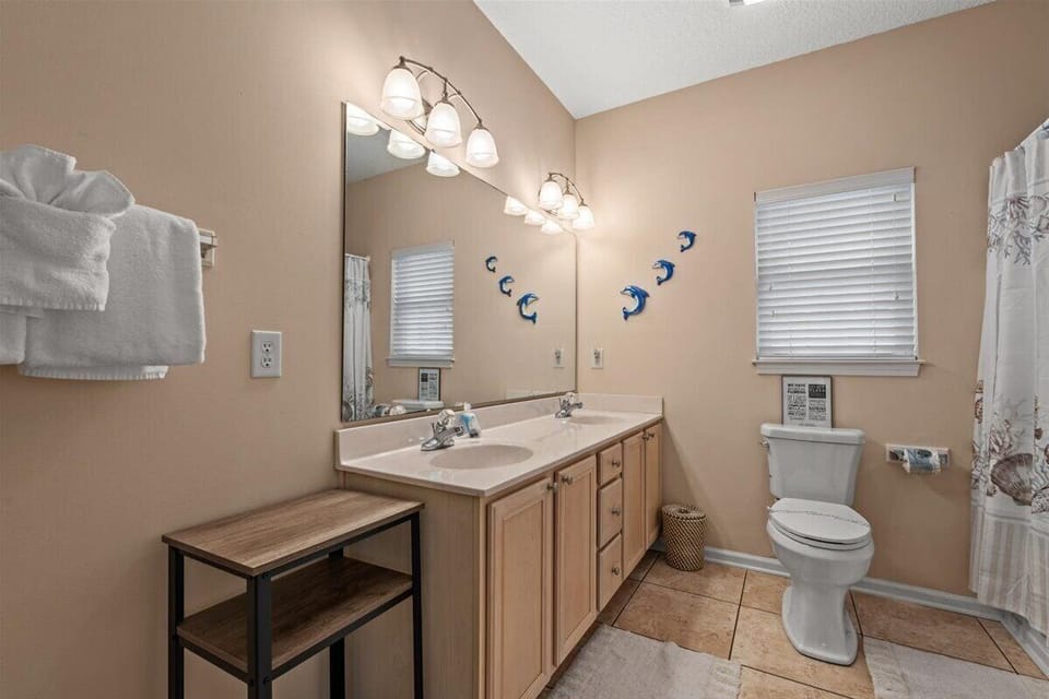 Refresh in your spacious bathroom featuring dual vanities, warm lighting, and playful dolphin decor that adds coastal charm to your daily routine.