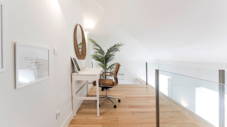Find your focus in this bright and serene loft workspace, offering a comfortable chair and ample surface for productivity while surrounded by a stylish, airy ambiance. The clever design with a glass railing creates an open, inspiring environment, perfect 