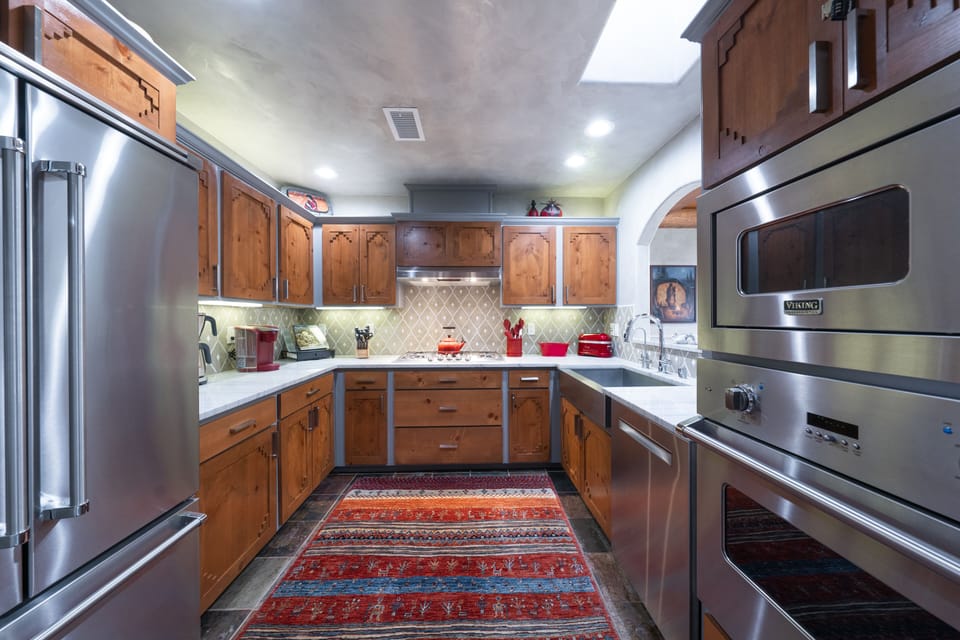A kitchen with stainless steel appliances and a rug.