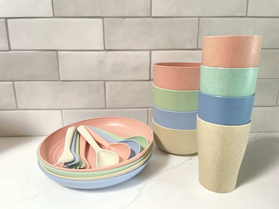 Kids kitchenware containing multiple plates, bowls, cups, forks, and knives.