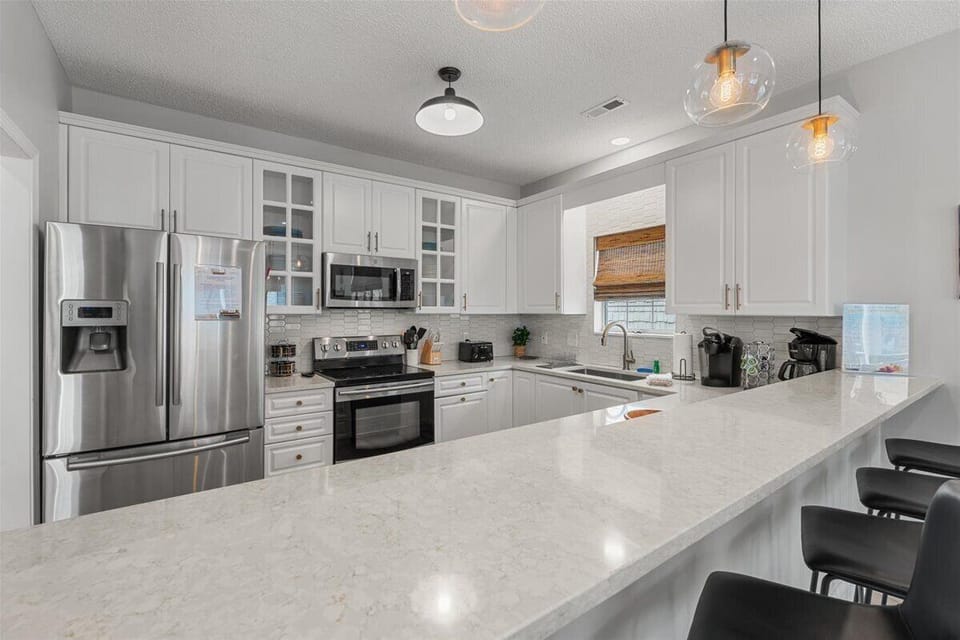 Cook together in your bright, fully-equipped kitchen featuring gleaming quartz counters, stainless appliances, and elegant pendant lighting.