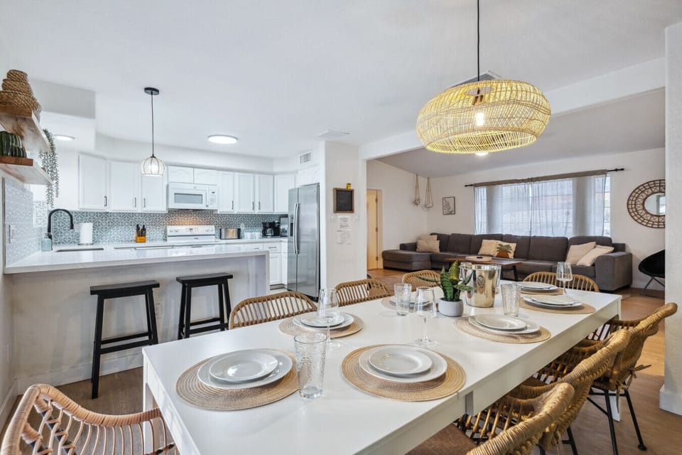 Dining area with set table, rattan chairs, and open kitchen