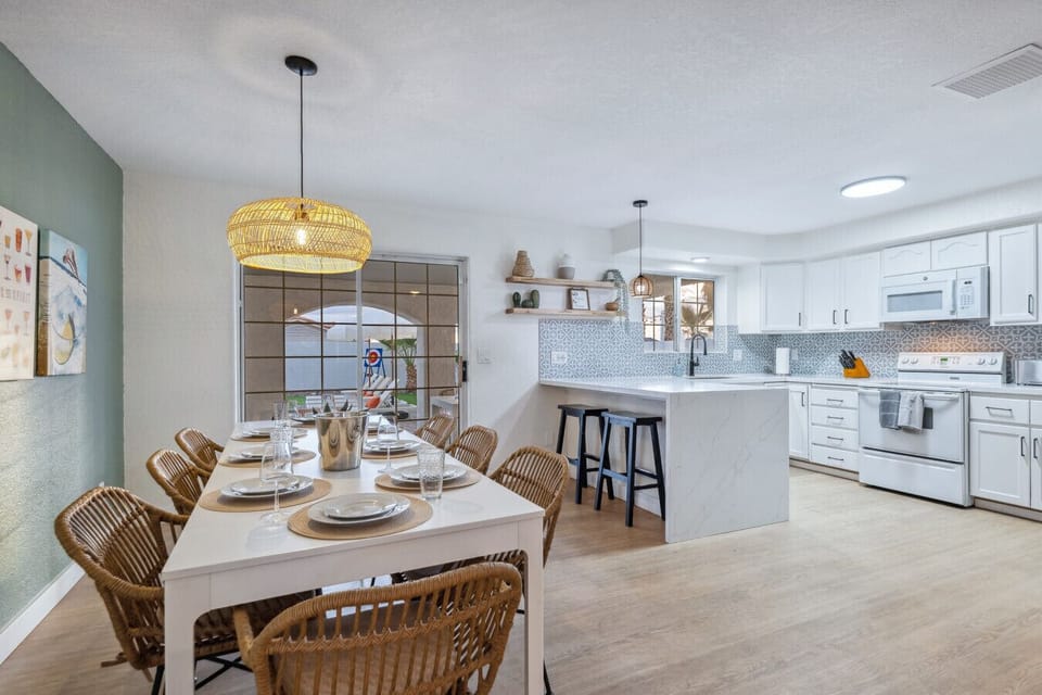 Dining area with rattan chairs, pendant lighting, and open kitchen view