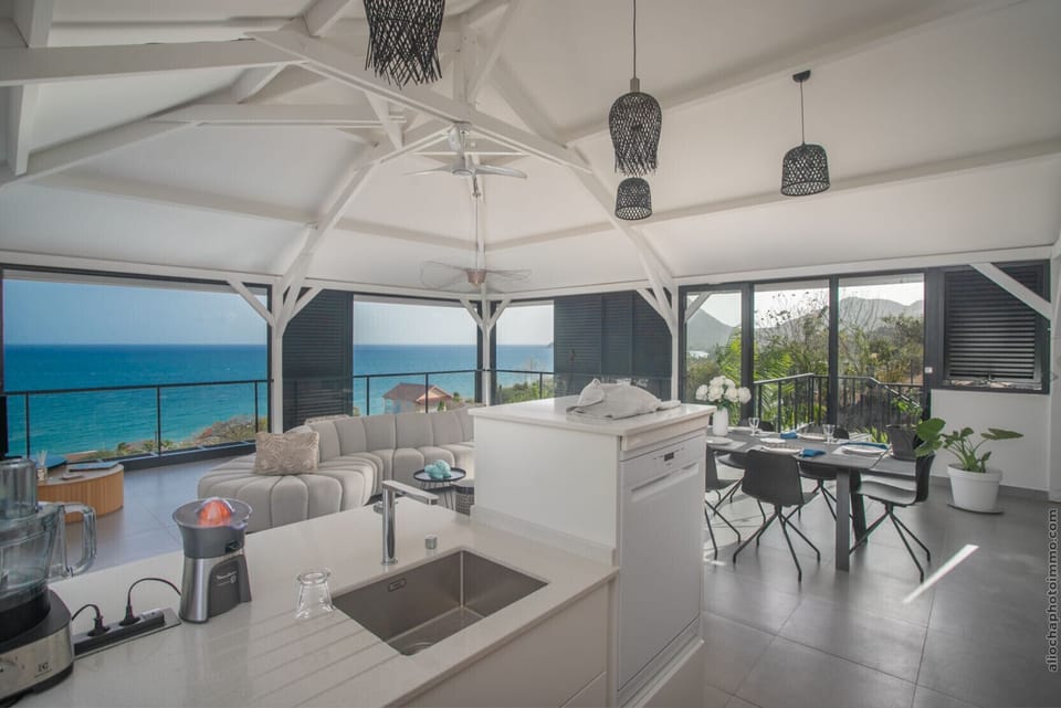 Large open-plan living space including lounge, kitchen and dining room, with panoramic views of Diamond Rock.