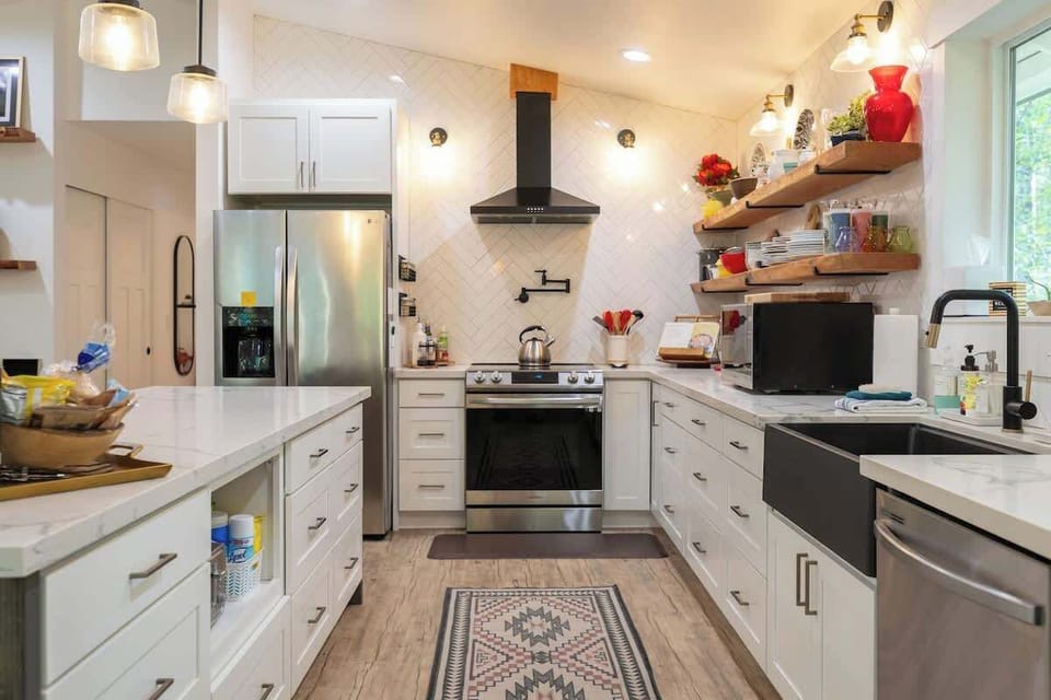 This Chef's kitchen features a 5-burner Samsung Range with an Airfryer and Pot filler, a microwave convection oven combo, a Farmhouse sink, a dishwasher, and an extra large Island for prepping and dining. 