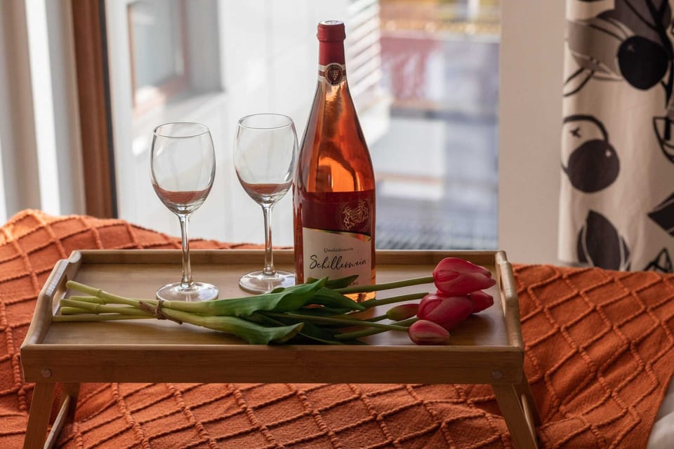 A beautifully set table with wine glasses and an orange tablecloth, creating a cozy and romantic dining atmosphere by the window.