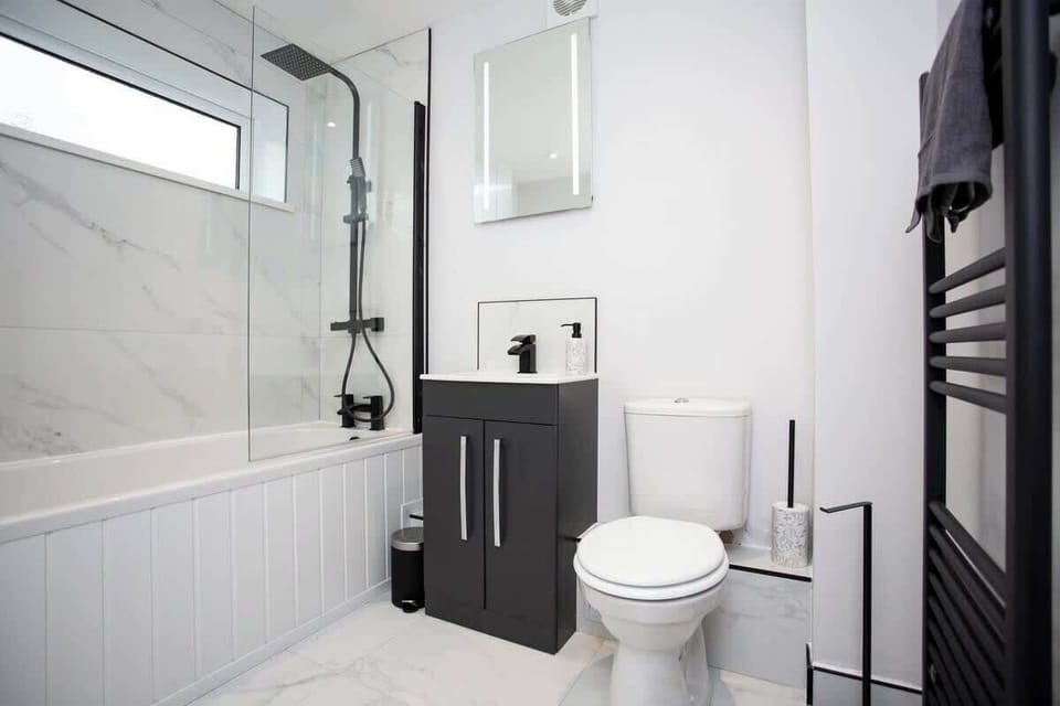 A wash in natural light, the spa-like atmosphere beckons with its sleek fixtures, rejuvenating rain shower, and towel rack. 