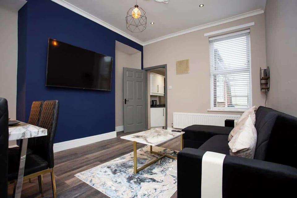 living room with large tv and sofa, coffee table and dining table and chairs. 