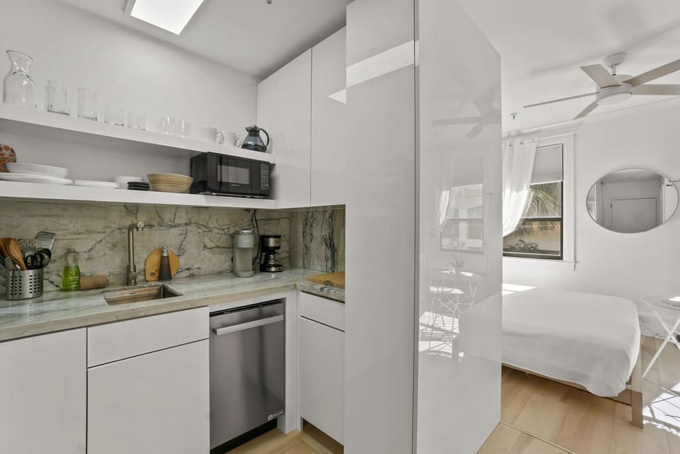 Kitchenette with microwave, mini fridge, Keurig coffee maker, glasses, plates, and cutlery
