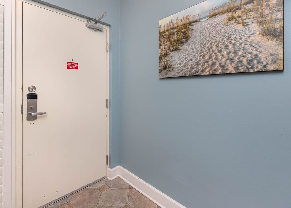 Step into a welcoming entryway featuring a beach-themed artwork and a secure door for your peace of mind