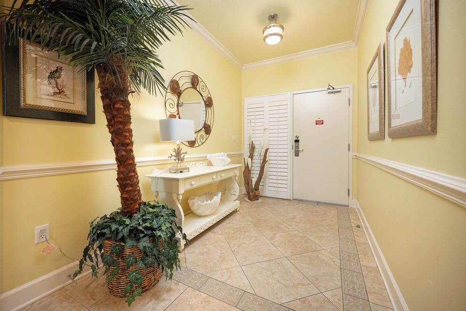 Step into a welcoming entryway featuring tropical decor, a stylish console table, and warm yellow walls