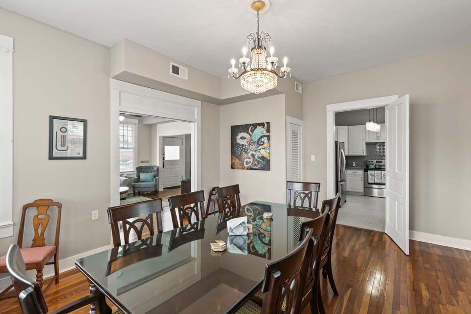 Dining with sunlight streaming through large windows and a chic chandelier.