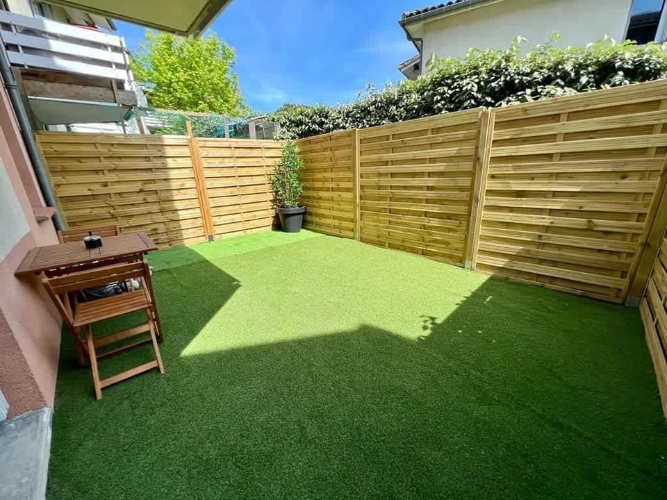 Terrasse privative avec table, chaises et chiliennes dans la résidence arborée, Le Cozen Toulouse