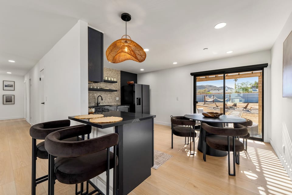 Share meals in the modern dining area, with breakfast-bar seating and direct access to the backyard.