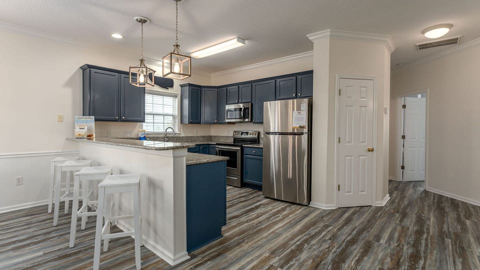 Step into your fully-equipped kitchen featuring elegant navy cabinets, granite counters, and stainless steel appliances—perfect for cooking memorable meals together.