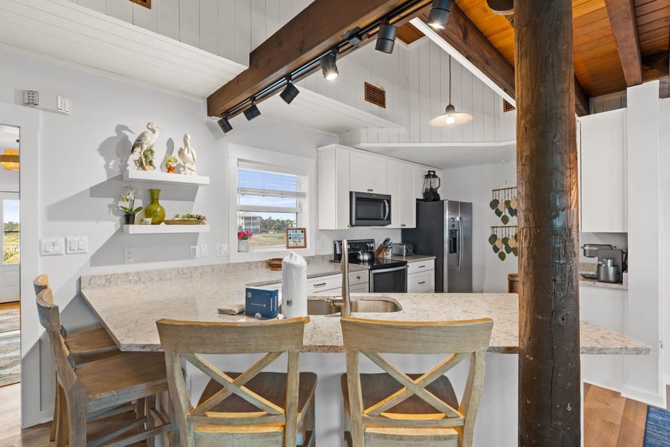 Your bright open kitchen invites you to gather around the island, where rustic wooden beams and modern appliances blend effortlessly for a cozy yet refined cooking experience.