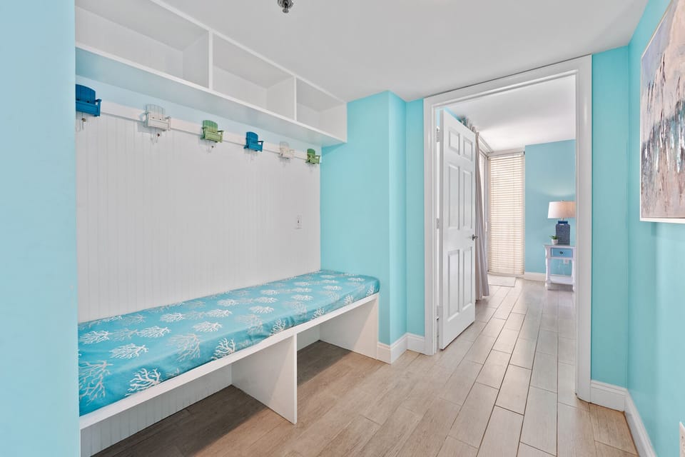 Kick off your sandy flip-flops at this cheerful built-in bench, complete with coastal-themed cushion and colorful hooks for your beach gear.