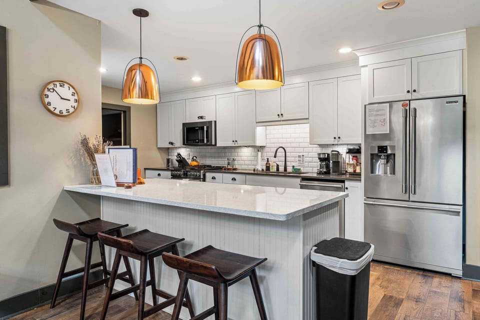 Modern kitchen with stainless steel appliances, a large island, and seating for three.