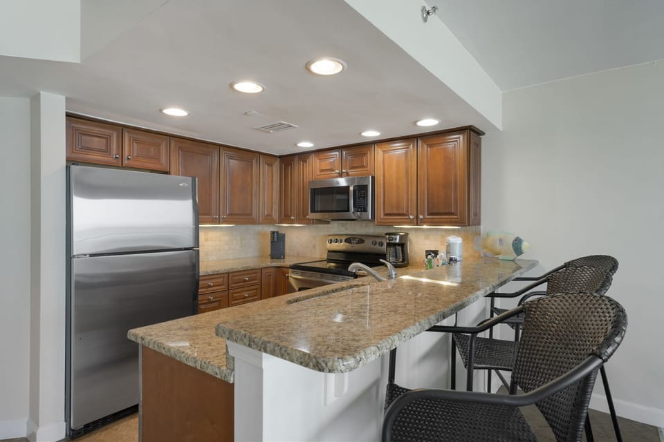 Fully equipped kitchen with modern appliances, bar seating, and ample counter space for preparing meals after a day on the beach.