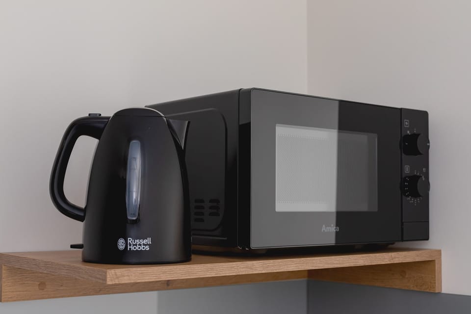 A microwave and kettle placed on a wooden shelf, adding practicality to the kitchenette.
