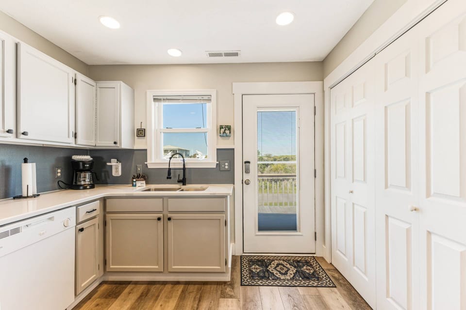 Step into the bright kitchen featuring white cabinets and a convenient laundry area hidden behind the scenes.