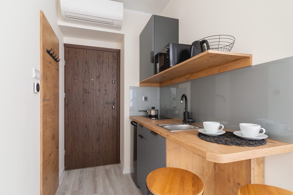 A kitchenette with a wooden counter and neatly arranged dishes and appliances.
