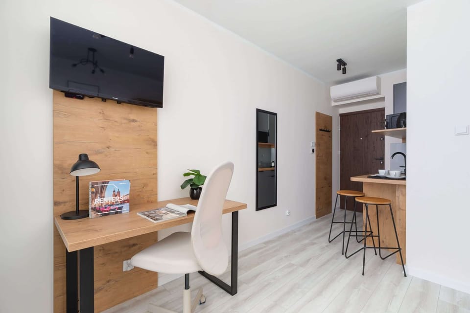 A multifunctional room with a TV, a workspace, and a stylish dining corner.
