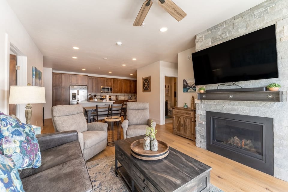 Settle into your cozy living space where rustic charm meets modern comfort, complete with a warming fireplace and open kitchen perfect for gathering.