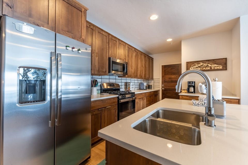 Your spacious kitchen awaits with warm wood cabinetry, gleaming counters, and premium stainless appliances—perfect for creating memorable meals.