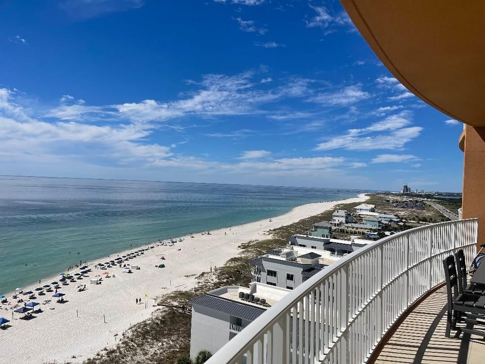 Relax on the balcony with salt-kissed air as umbrellas and swimmers dot the beach below