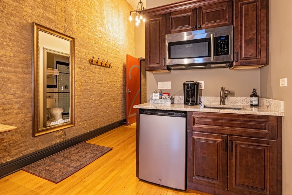 The kitchenette from a wider angle - the full-length mirror, coat hooks, and orange door all visible from here.